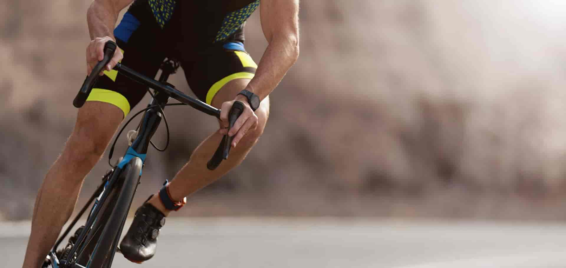 Cyclist in black and neon yellow kit leaning into a turn on a road bike.