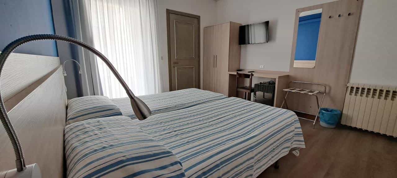 Twin beds with blue and white striped linens in a hotel room with a flexible reading lamp.