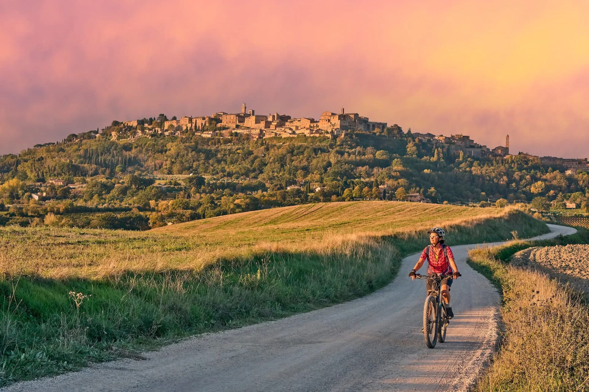 Mountain biking on a dirt road toward Montepulciano in Tuscany at sunset.