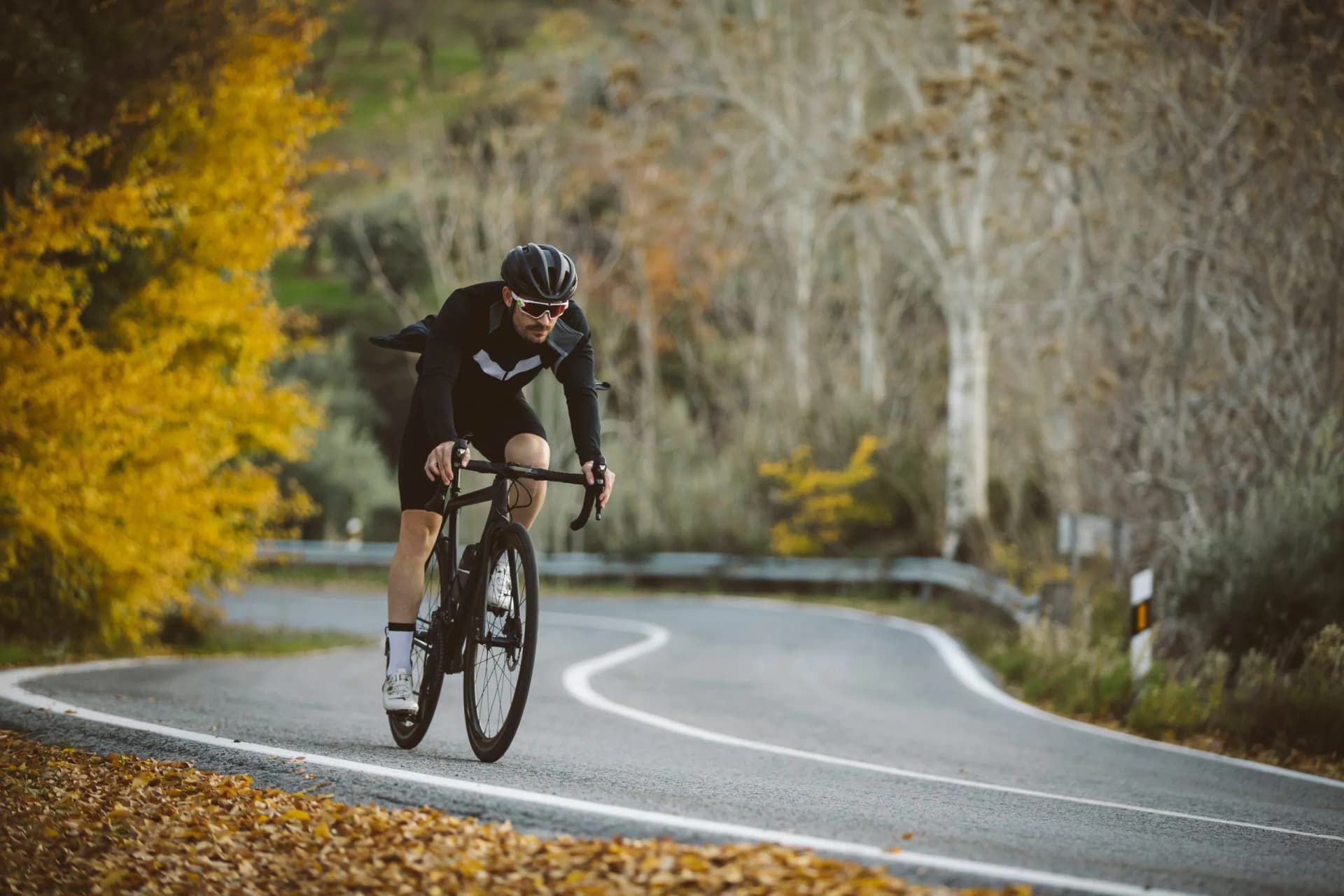 Road cyclist on winding mountain road with autumn foliage in the Dolomites