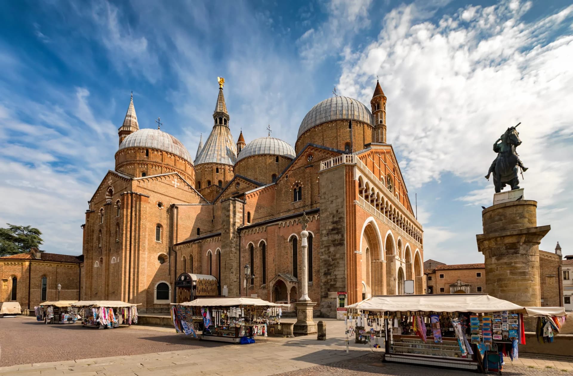 Basilica of Saint Anthony with domes, statue, and souvenir stalls in Padua.