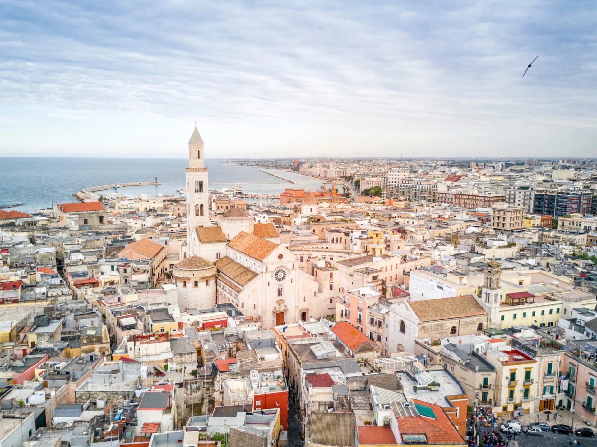 Aerial view of Bari cityscape with cathedral and Adriatic Sea coastline under cloudy sky