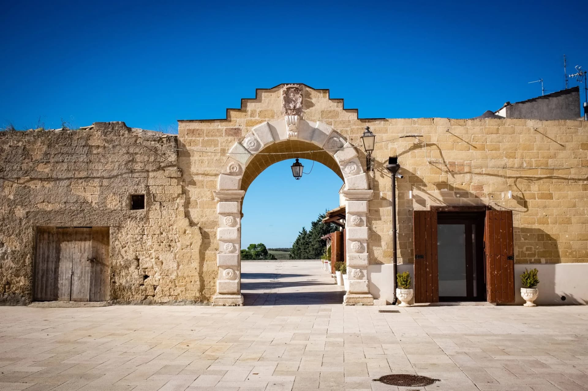 Stone archway entrance in historic town square under bright blue sky, view to countryside.