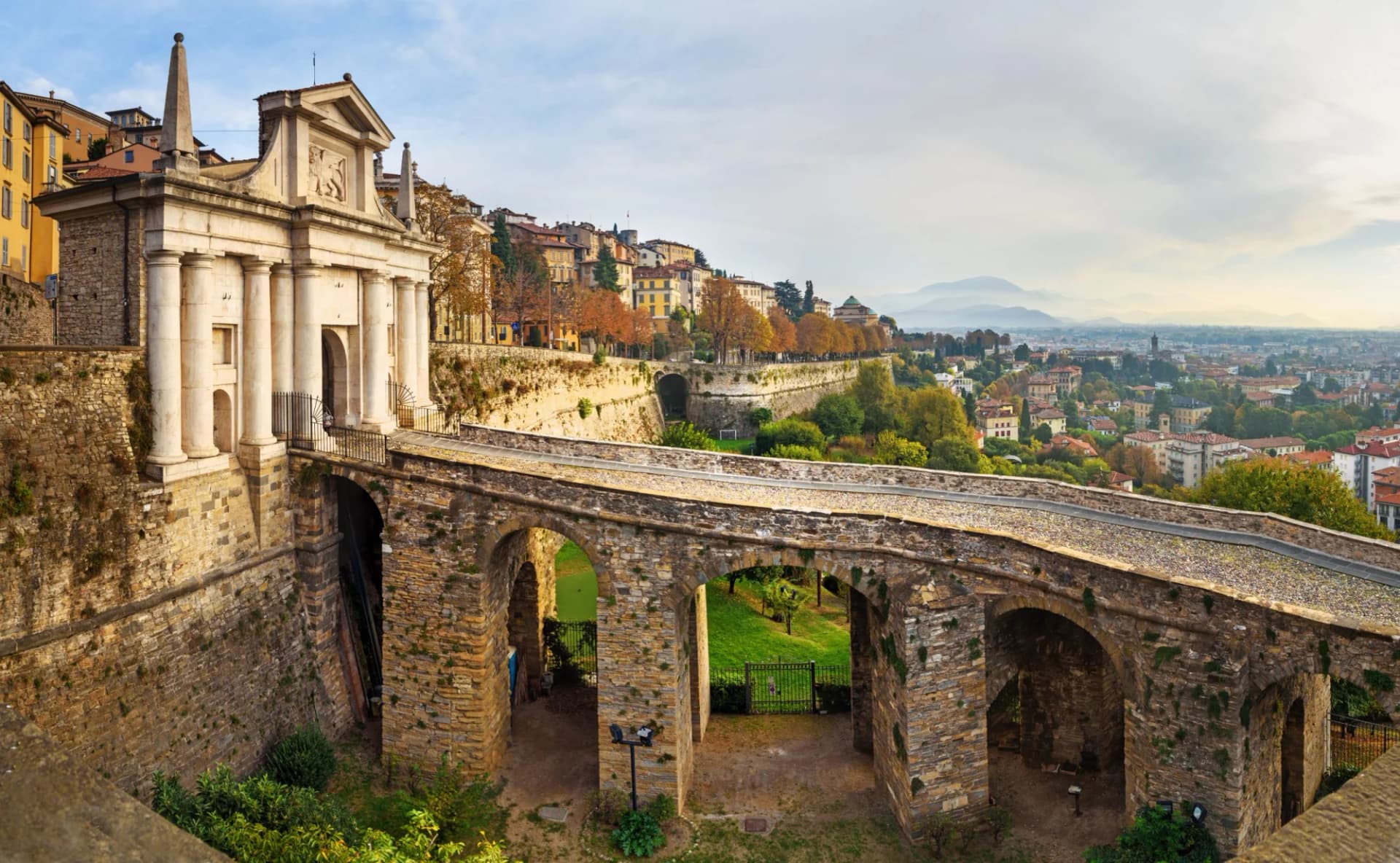 Porta San Giacomo gate and stone bridge overlooking the city and mountains of Bergamo.