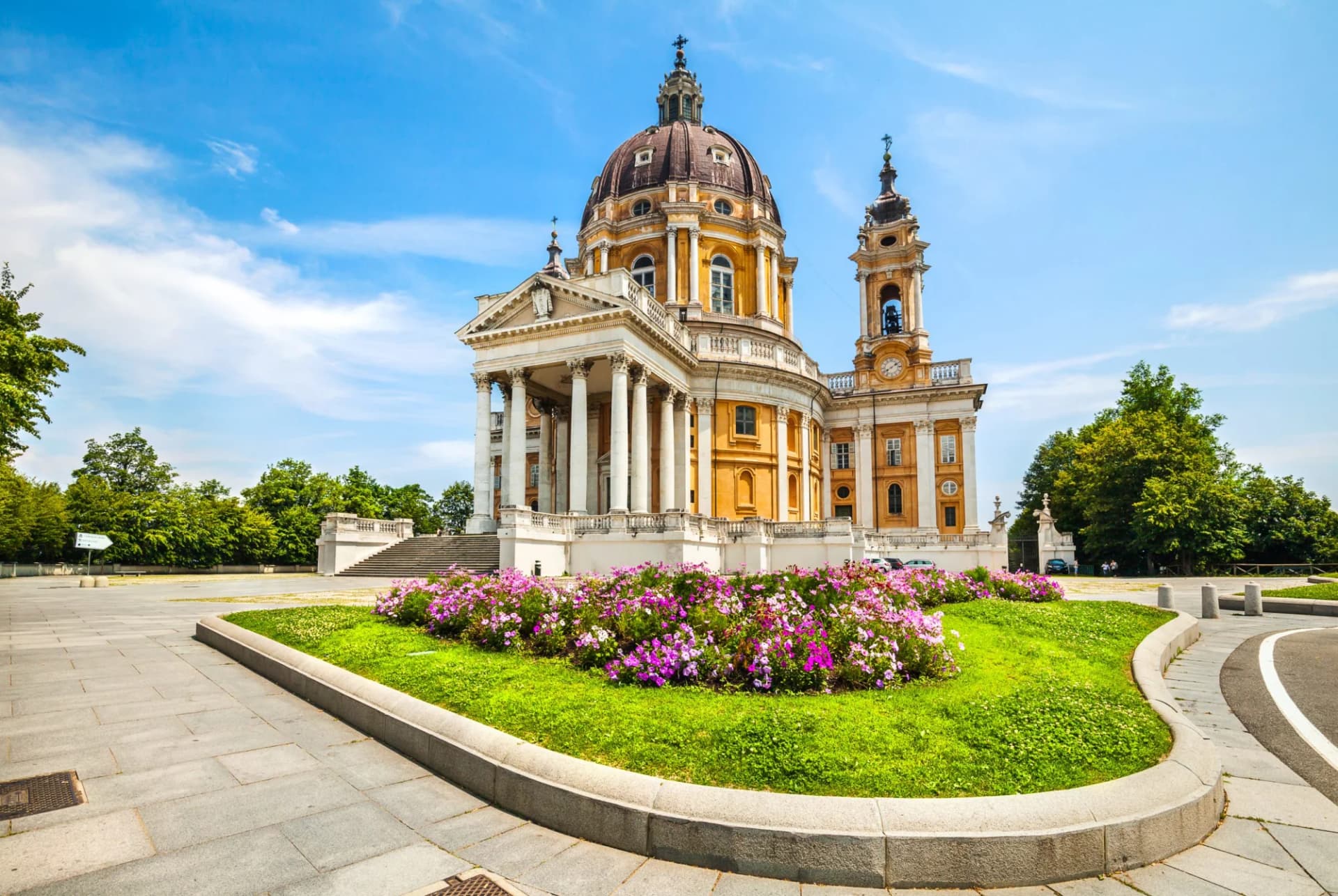 Basilica of Superga in Turin, Italy, with a dome, bell tower, and flower garden.