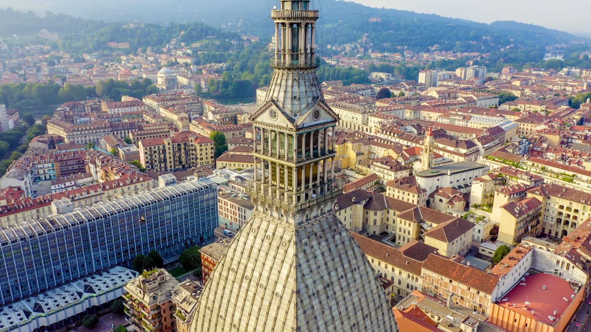 Rooftop view of the Mole Antonelliana spire overlooking the dense city of Turin, Italy.