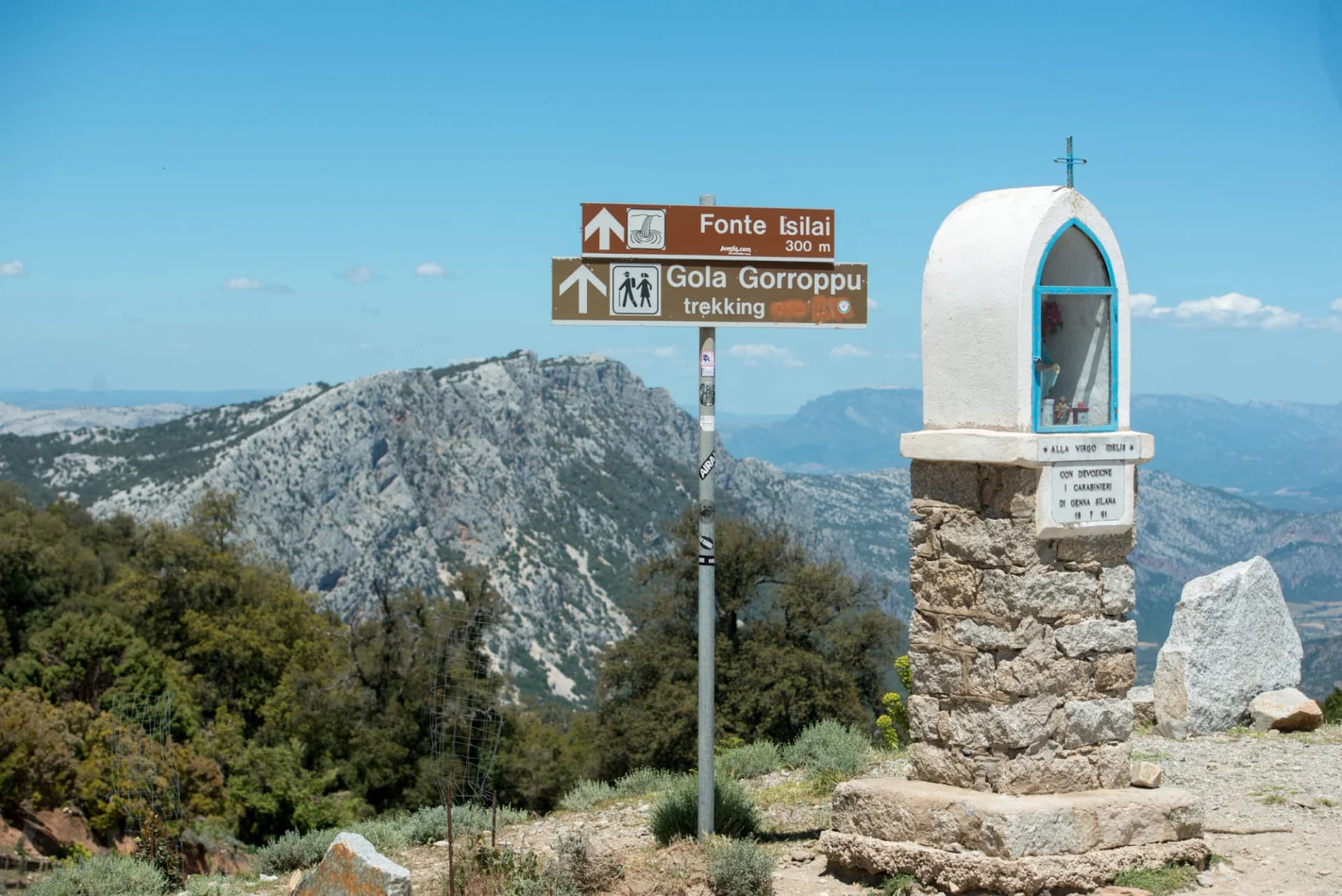 Trekking signs for Gola Gorropu and shrine near rocky mountains at Genna Silana.