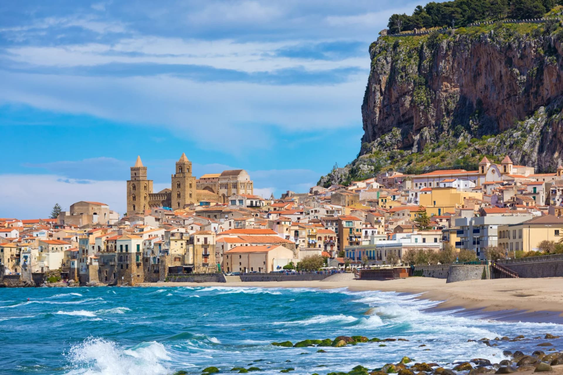 Coastal town with historic cathedral nestled against a large cliff on the west coast of Sicily.