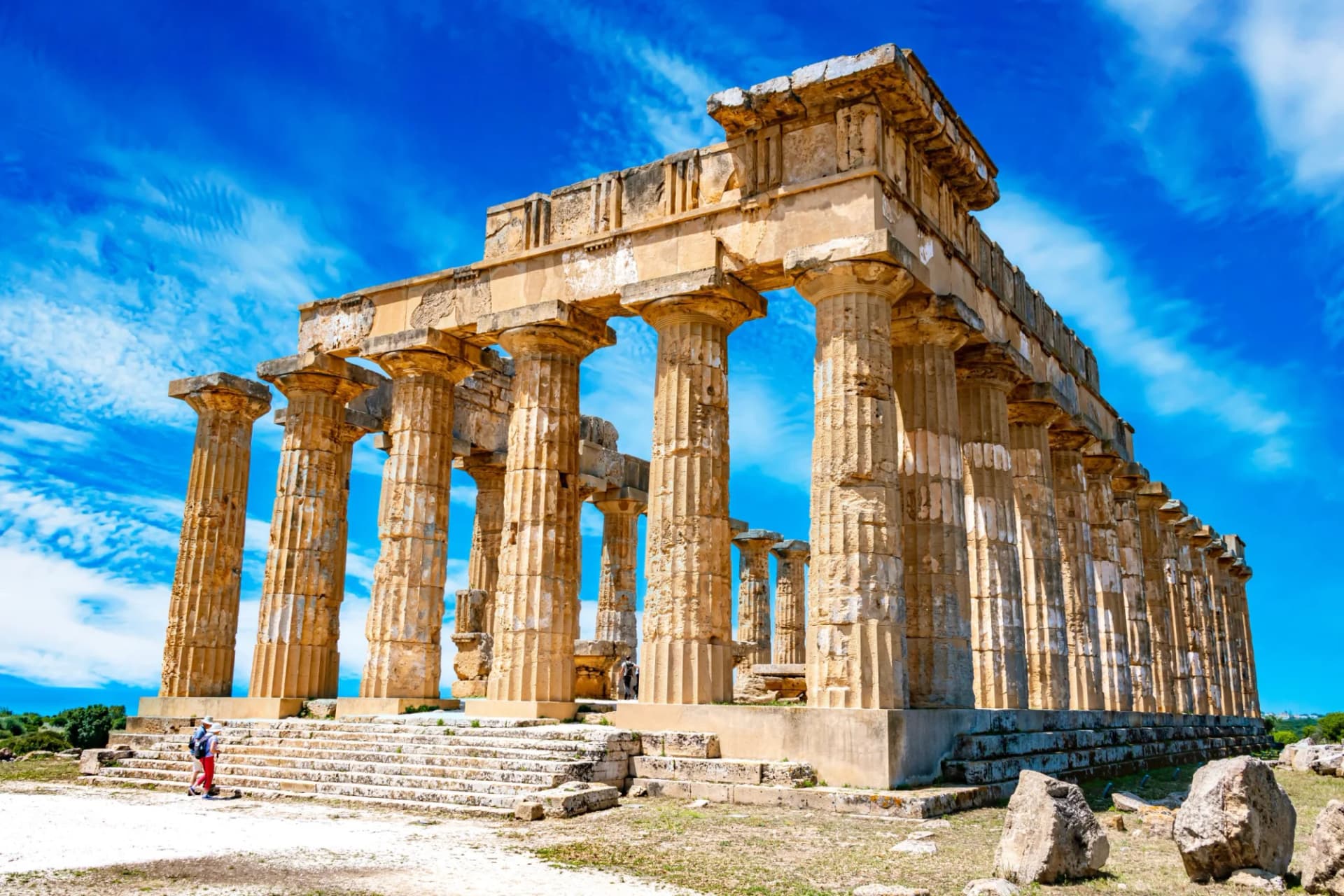 Ruins of the Temple of Hera at Selinunte under a bright blue, cloudy sky.