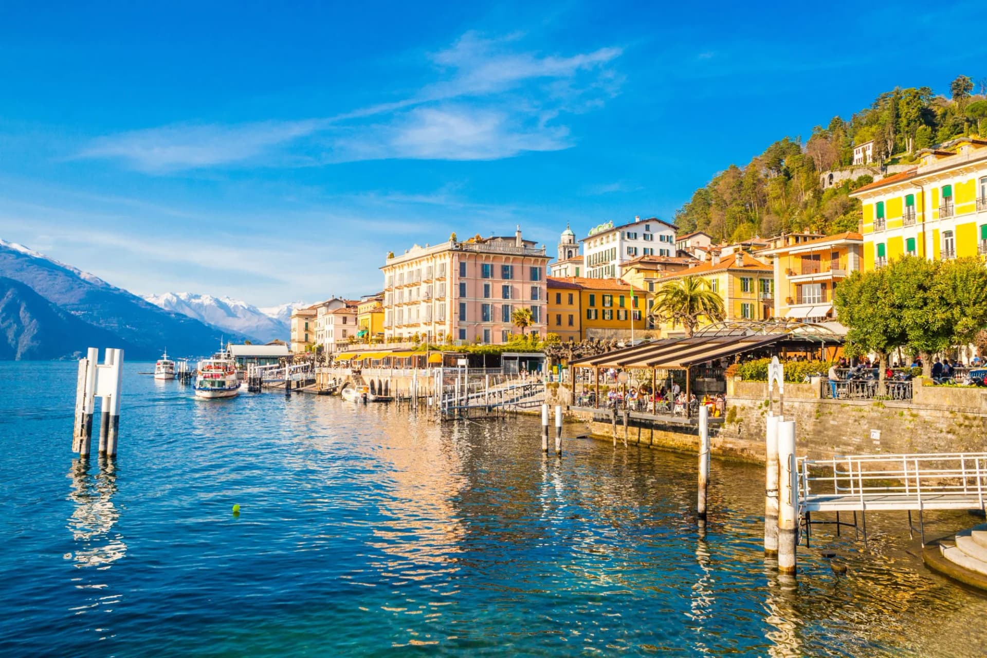 Colorful buildings along Lake Como waterfront with snow-capped mountains in background