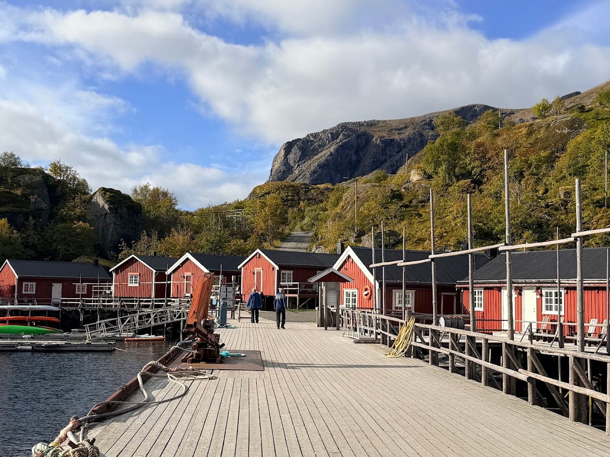 Wooden pier with red cabins and mountains in coastal setting
