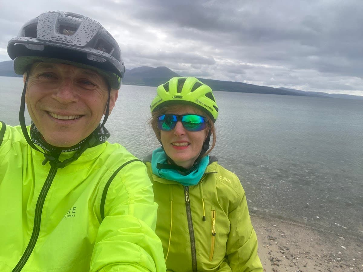 Cyclists in high-visibility jackets and helmets taking a selfie by a lake
