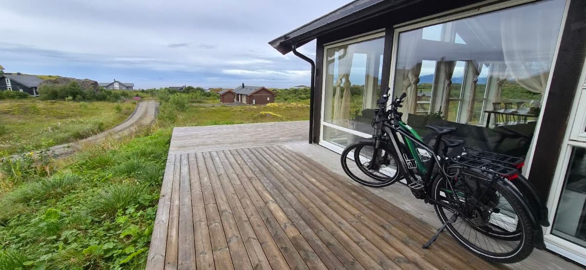 Bicycles parked on a wooden deck outside a glass-walled building with a coastal landscape view