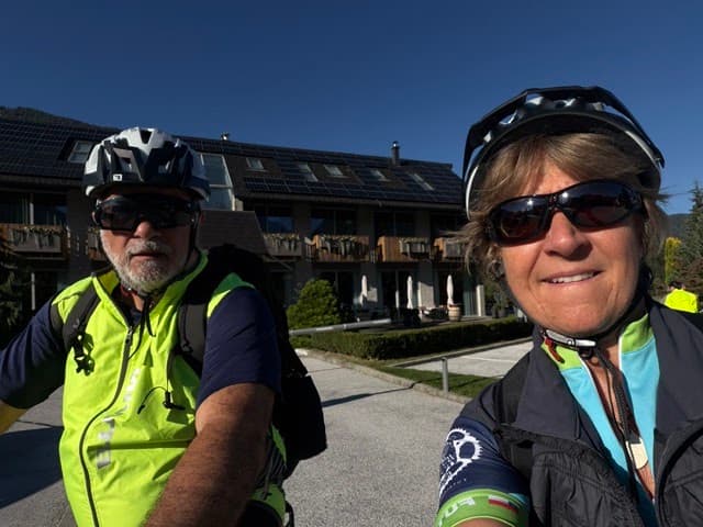 Cyclists wearing helmets and sunglasses outdoors in front of building