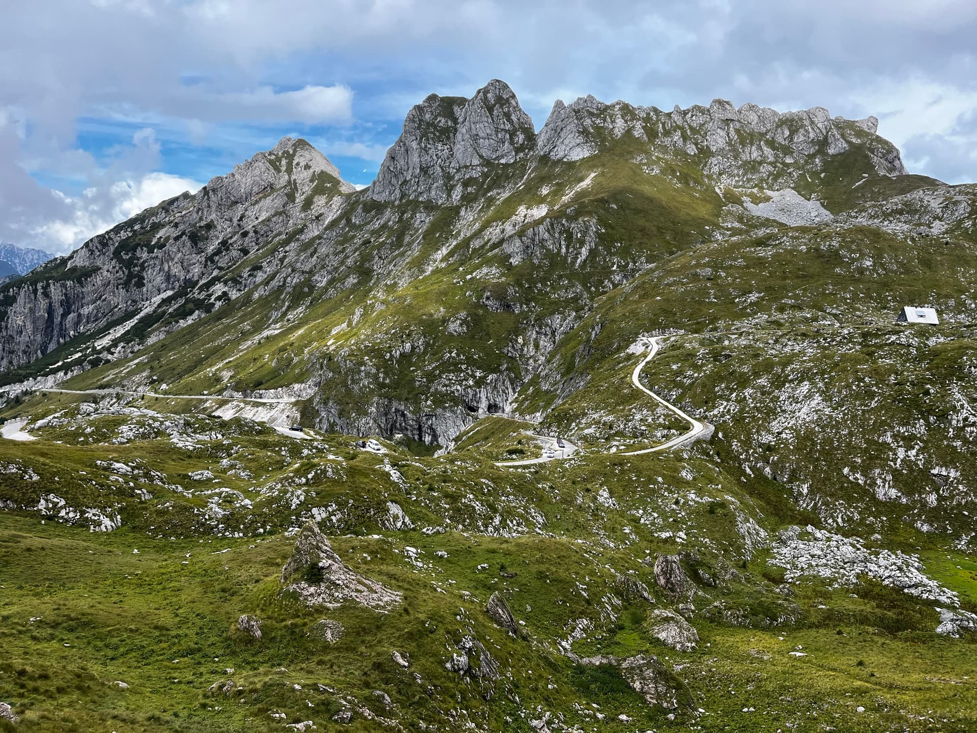 Winding mountain road traversing a green alpine landscape with rocky peaks