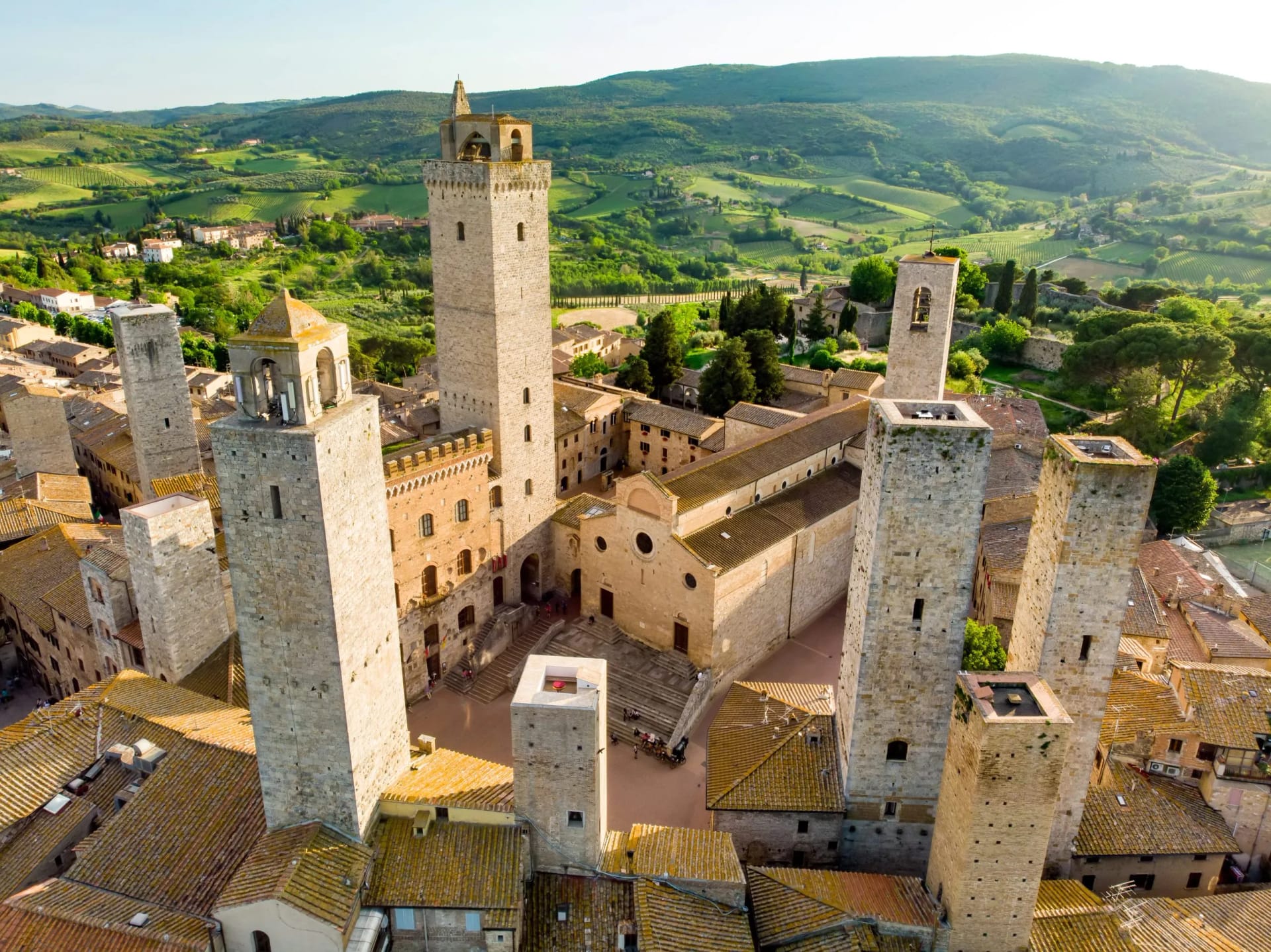 Towers of San Gimignano in Tuscany overlooking green rolling hills and vineyards.