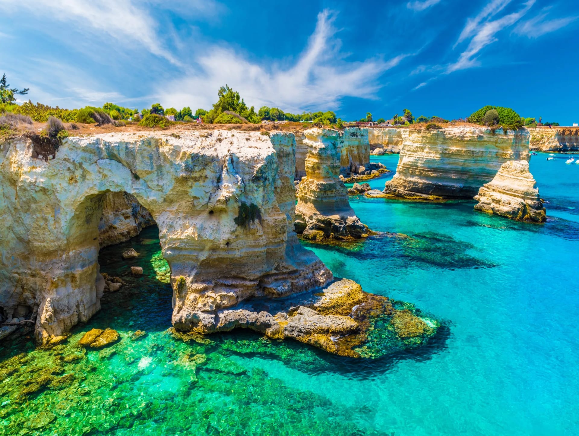 White limestone sea stacks and arches with turquoise water in Puglia coastline.