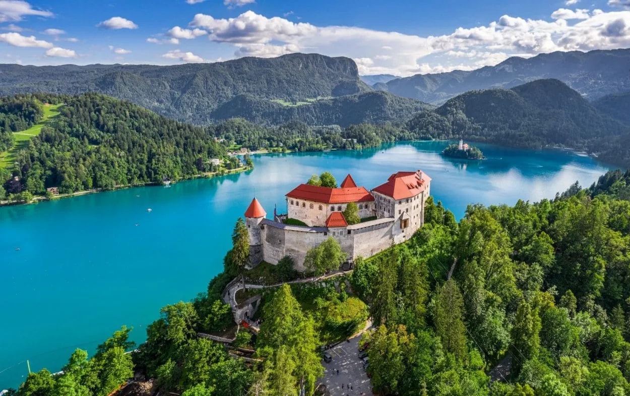 Lake Bled Castle overlooking turquoise water with island church and forested mountains in Slovenia.