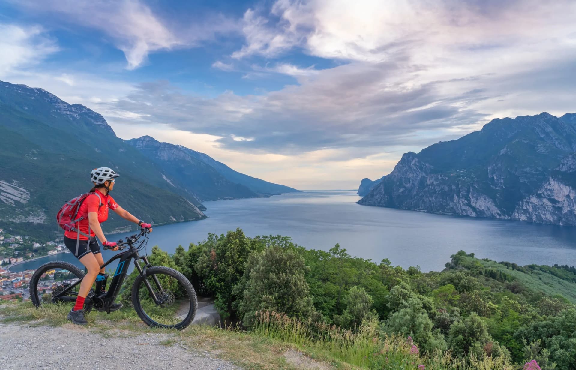 Mountain biking above a large lake with steep cliffs and a small town below