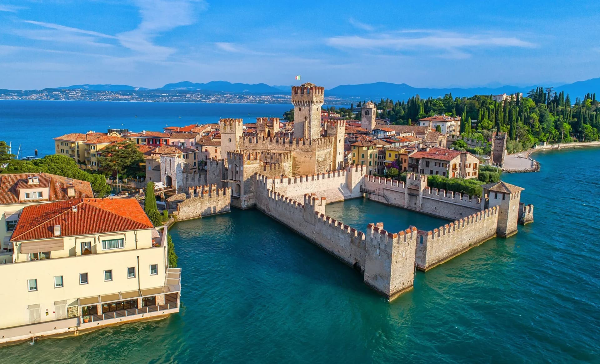 Scaligero Castle surrounded by turquoise water in Sirmione on Lake Garda, Italy.