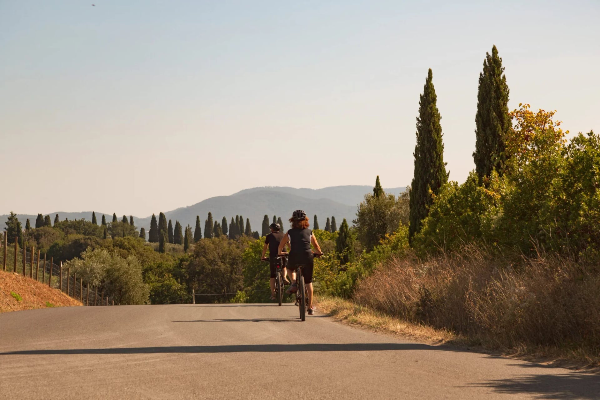 Cycling on paved road through Tuscan landscape with cypress trees and rolling hills