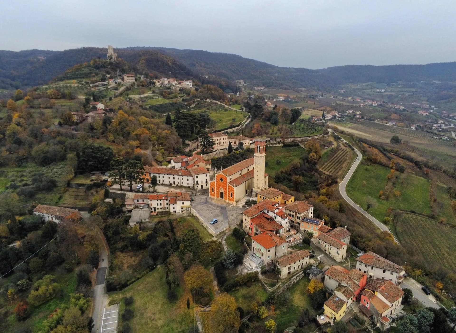 Hilltop village with church and castle ruins in rolling Nanto-Veneto landscape, autumn.