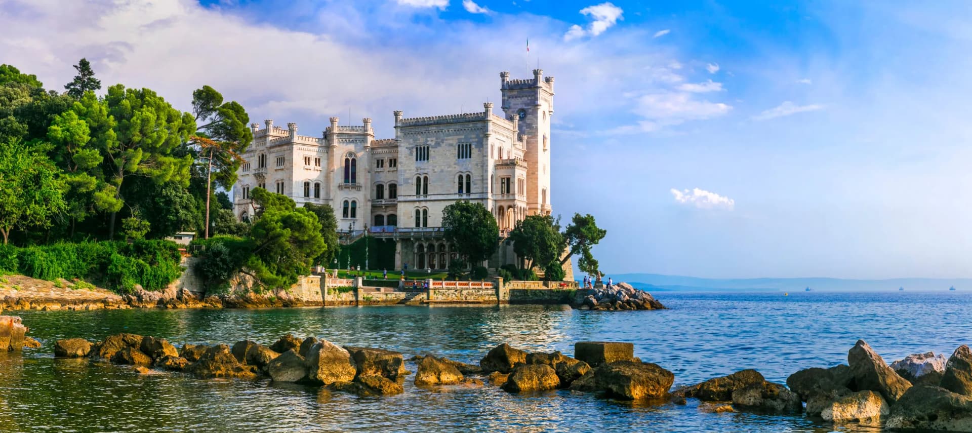 Miramare Castle on the Adriatic coast with lush trees and blue sky