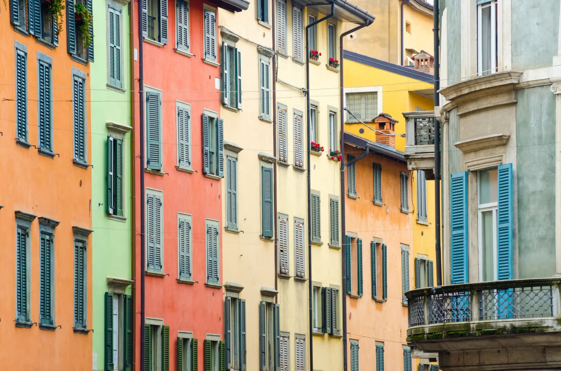 Colorful historic buildings with many closed and open window shutters in Bergamo, Italy.