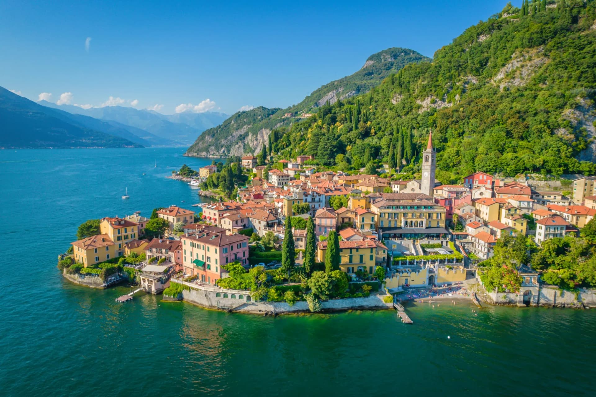 Colorful lakeside village with terracotta roofs nestled against steep, green mountains on Lake Como.
