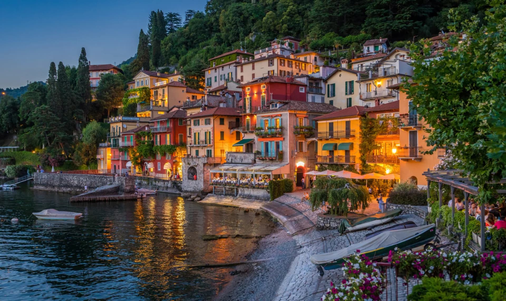 Colorful lakeside village houses climbing a steep hill at dusk, Varenna, Italy.