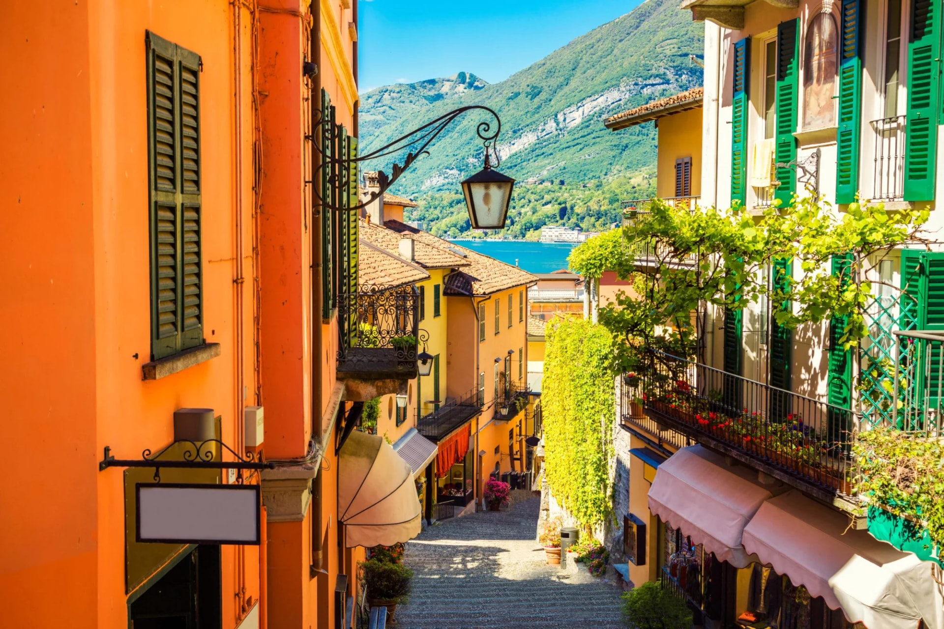 Picturesque and colorful old town street in Bellagio overlooking Lake Como and green mountains.