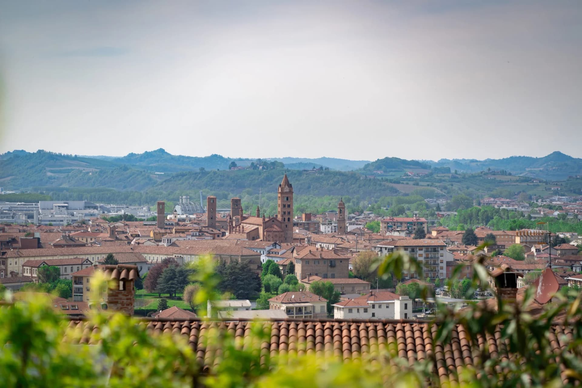 Town of Alba in Cuneo, Piemonte, Italy, with terracotta roofs and rolling green hills.