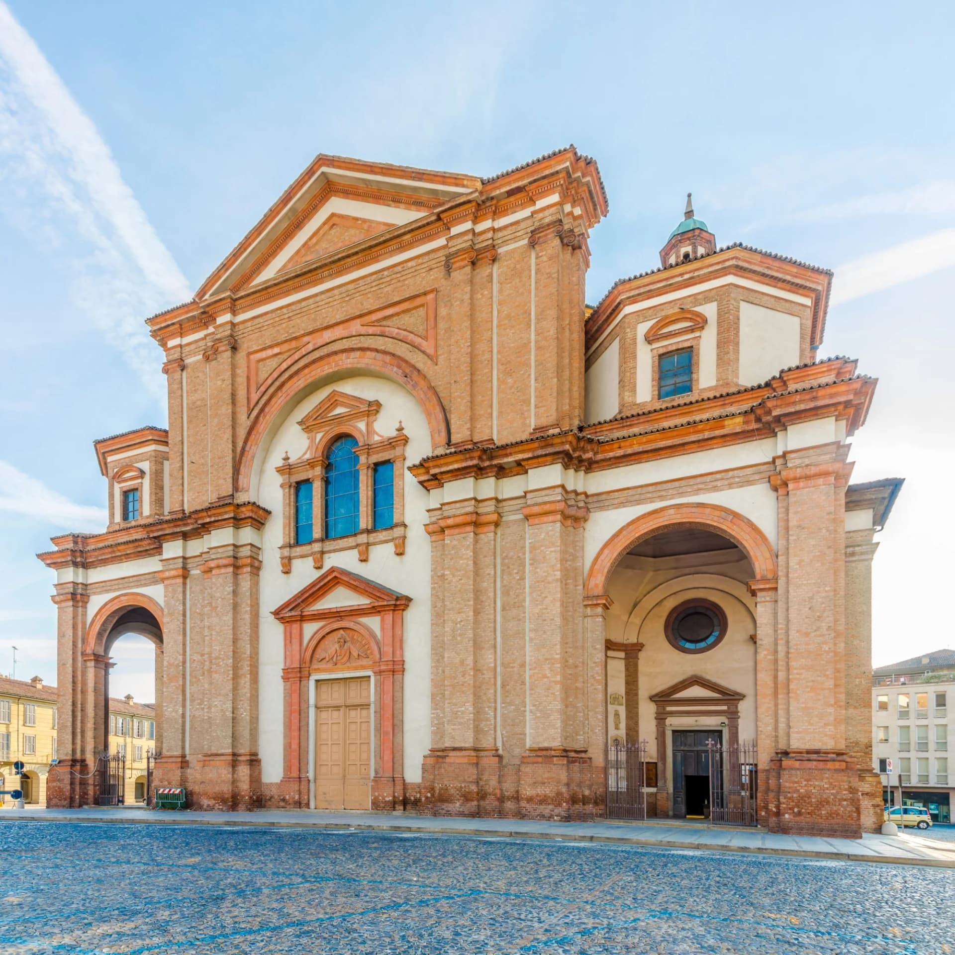 Baroque church facade with brickwork in the streets of Voghera, Italy, on a sunny day.