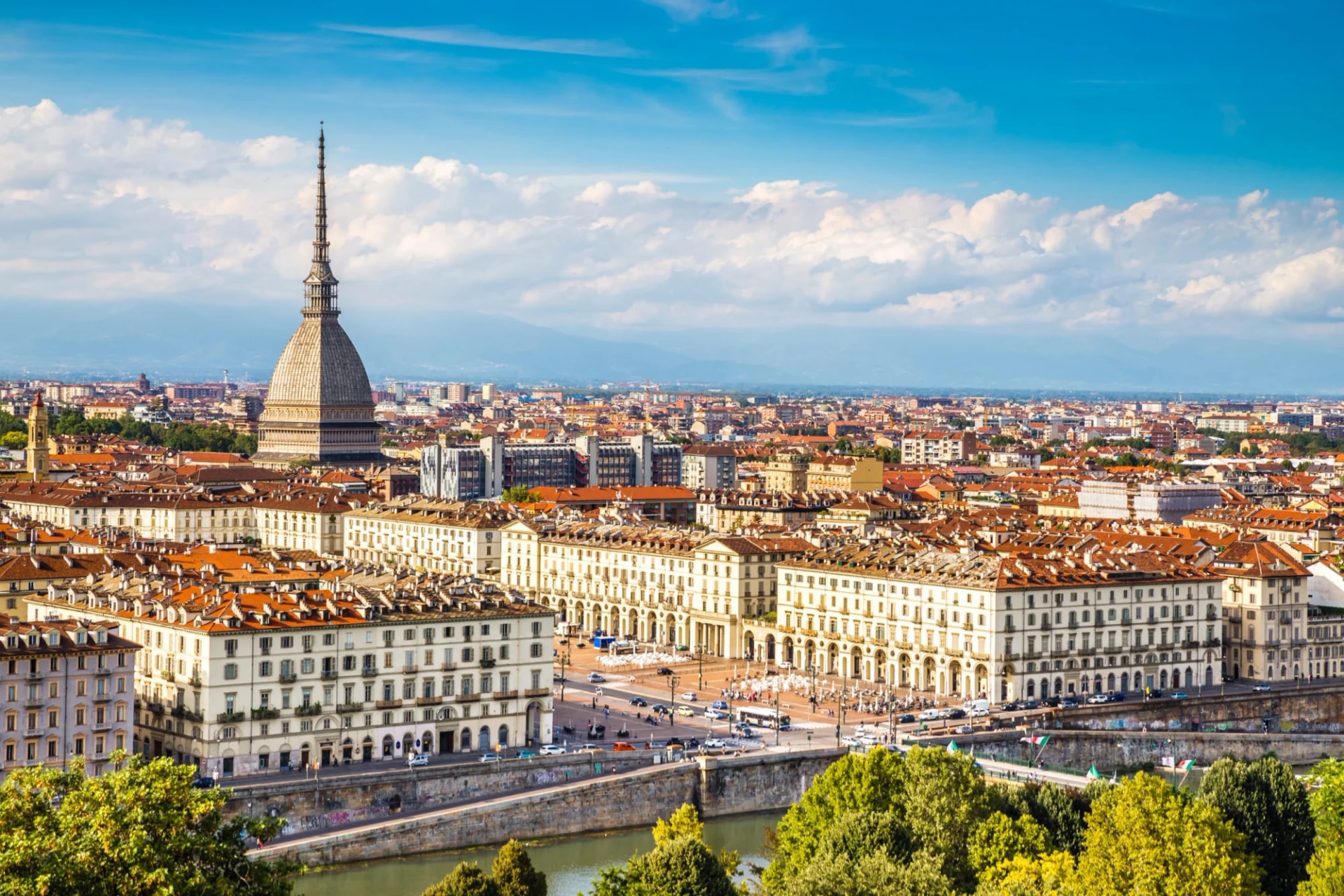 View of Turin centre with Mole Antonelliana, historic buildings, and river under blue sky.