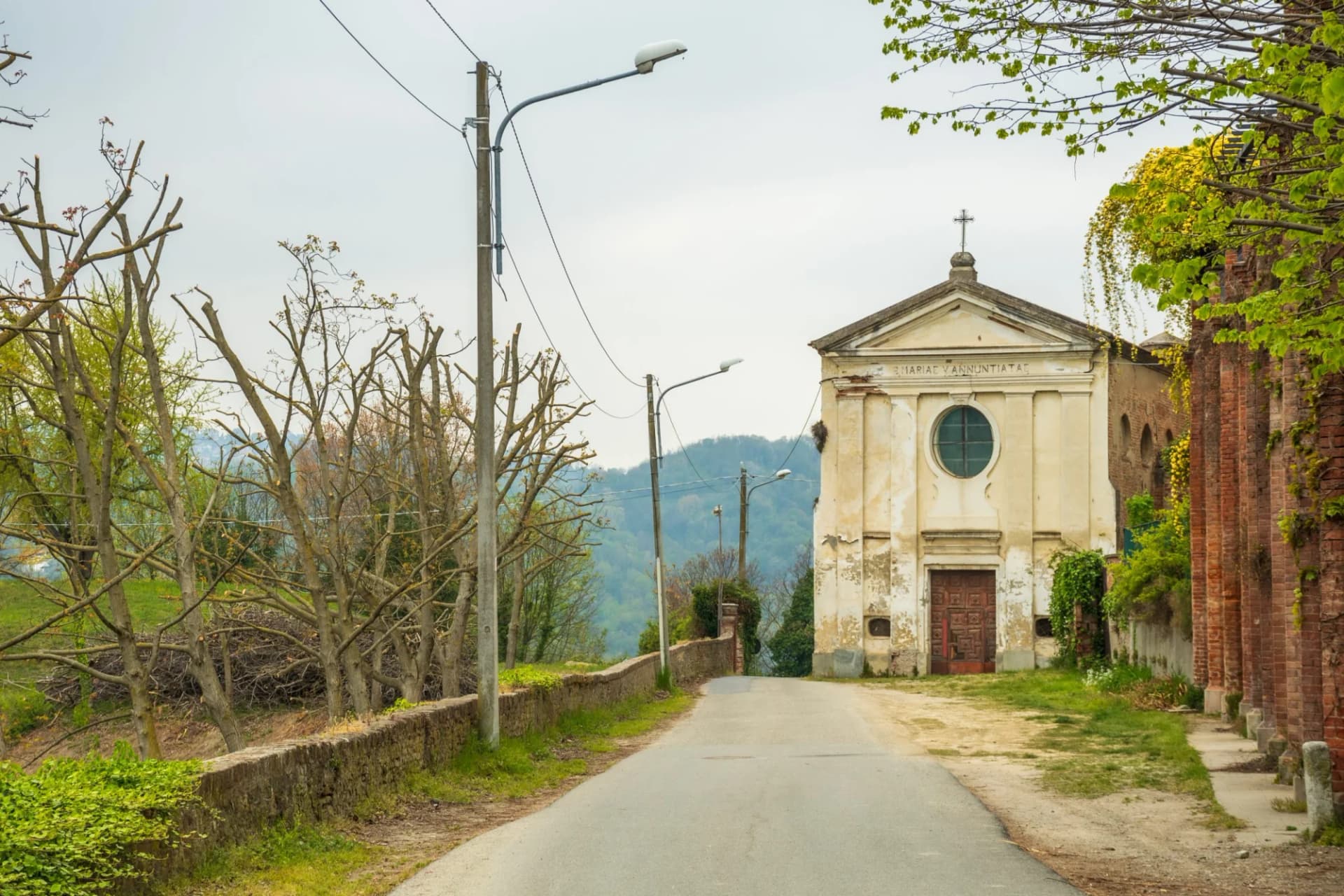 Old church in San Sebastiano da Po, Torino, Piedmont, Italy, with a road leading uphill.