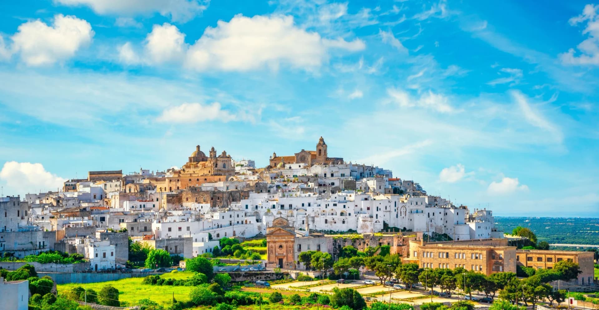 White-washed hilltop town with churches under a bright blue sky in Bari, Apulia, Southern Italy.