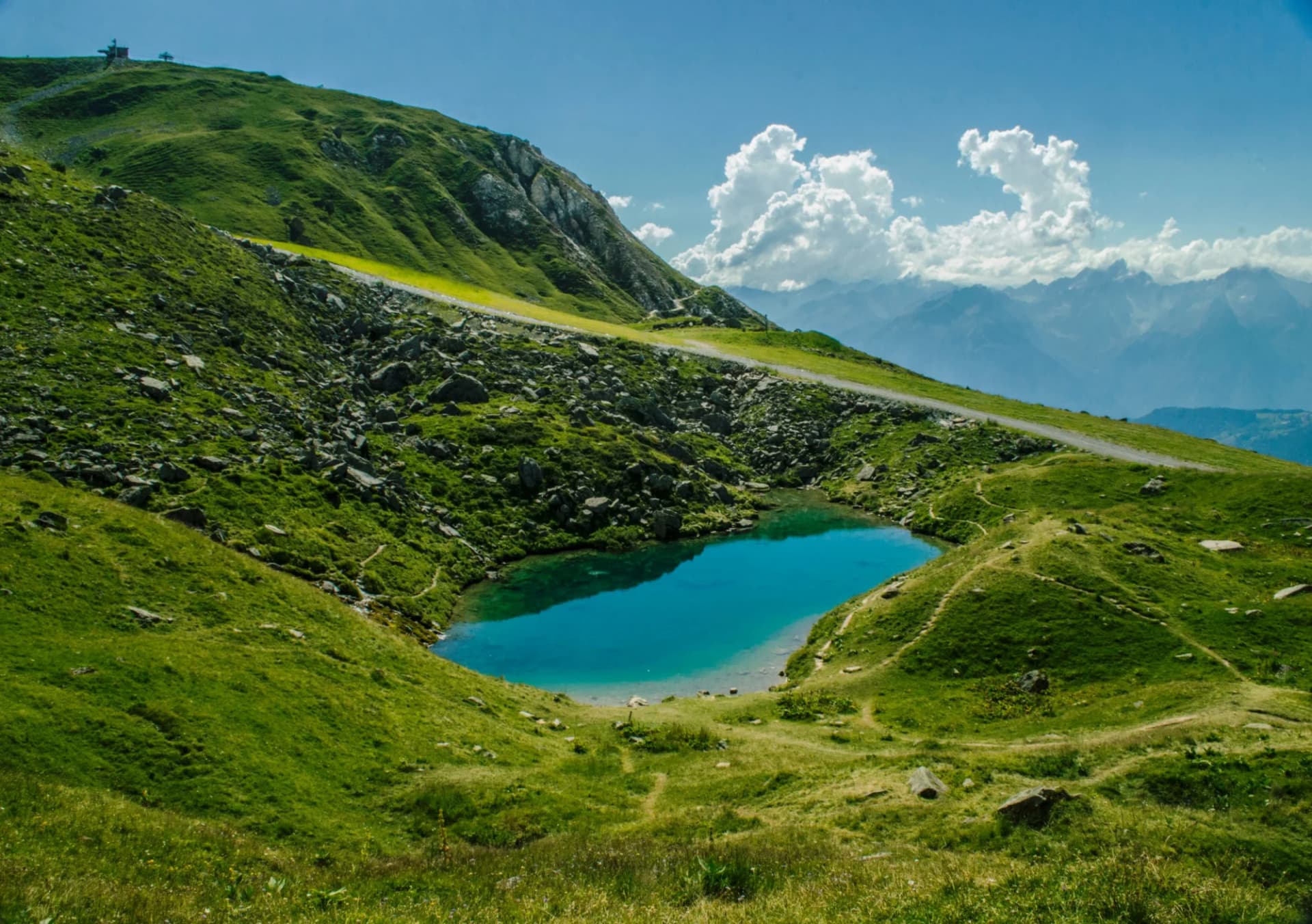 Alpine lake with turquoise water nestled in green, rocky mountains near Col de la Madeleine.