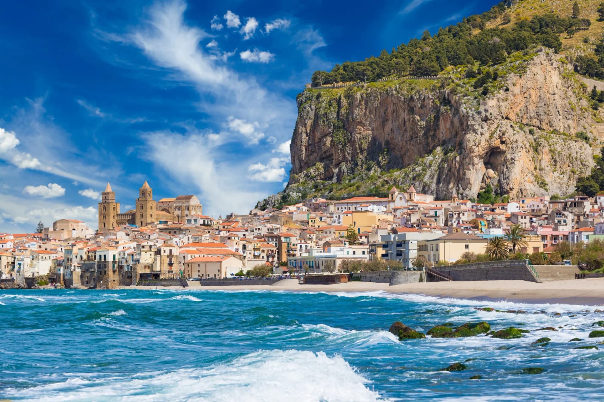 Cefalu resort town with cathedral nestled against a large cliff above the Tyrrhenian Sea.