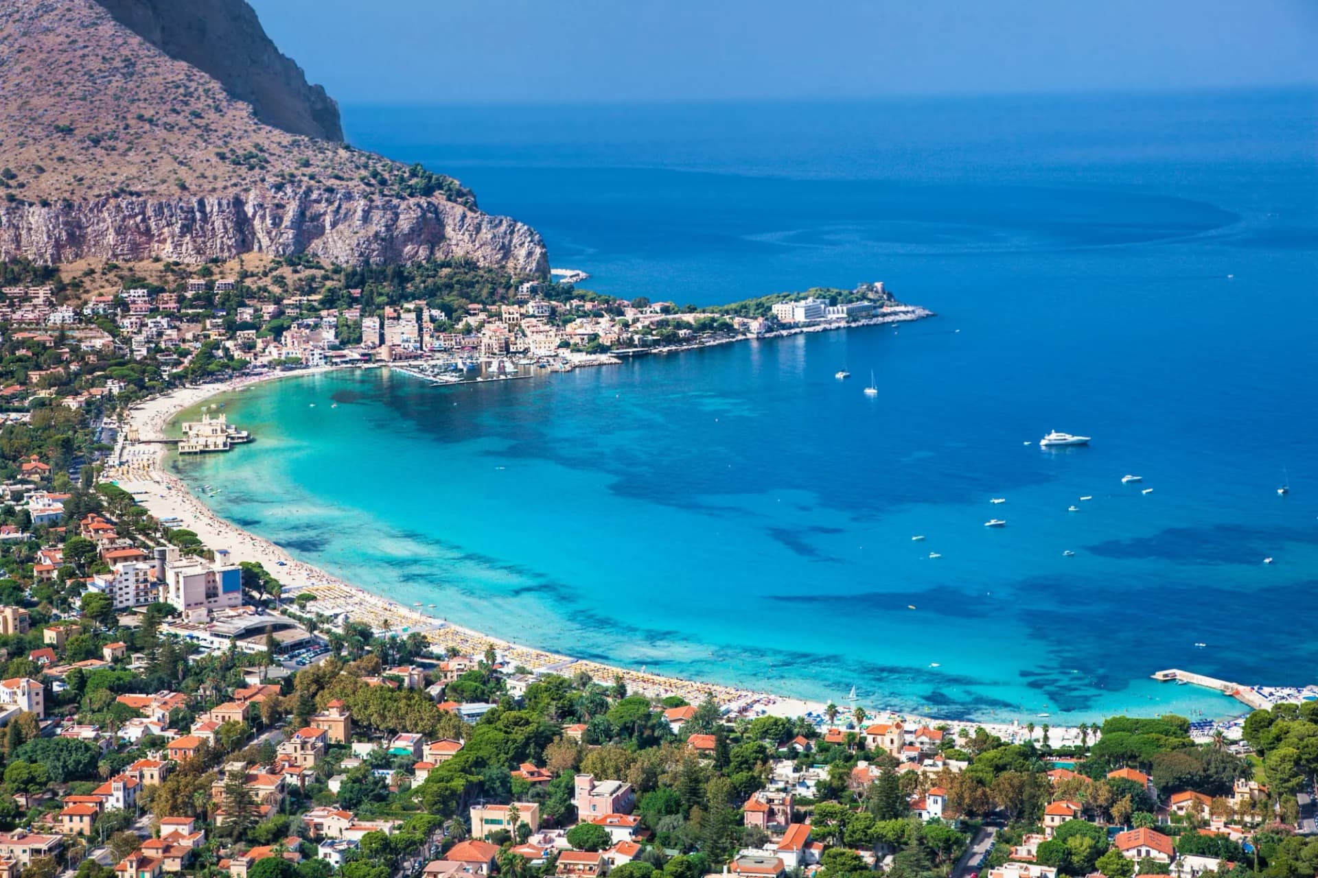 Panoramic view of Mondello white beach in Palermo, Sicily with turquoise water and boats.