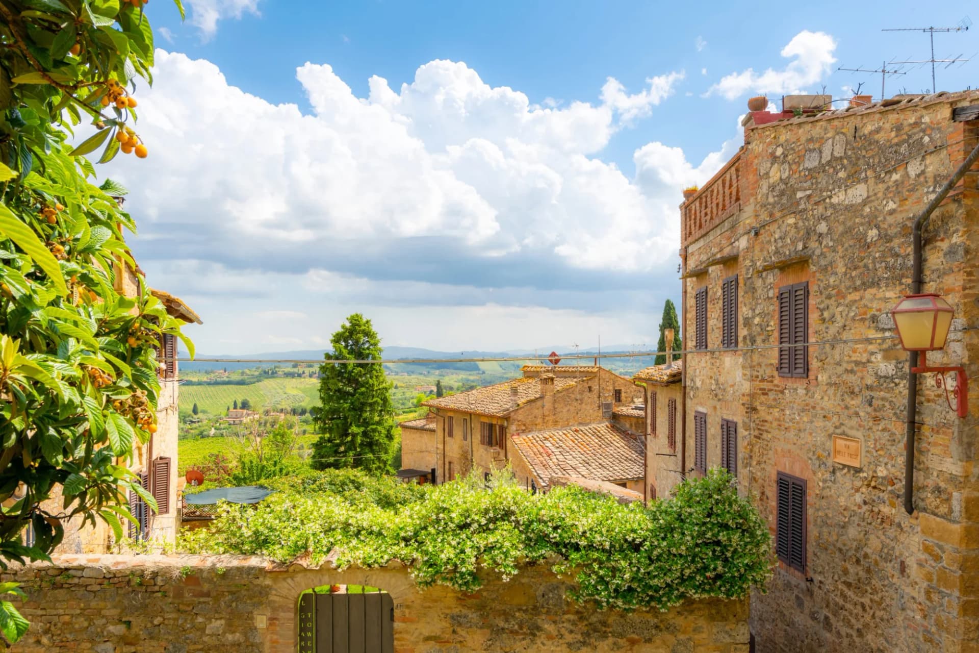 View of San Gimignano's stone buildings overlooking Tuscan countryside and rolling hills.