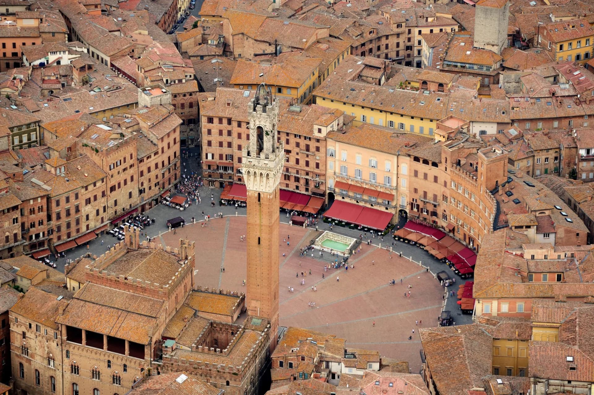 Aerial view of Siena's Piazza del Campo with the Torre del Mangia and terracotta rooftops.