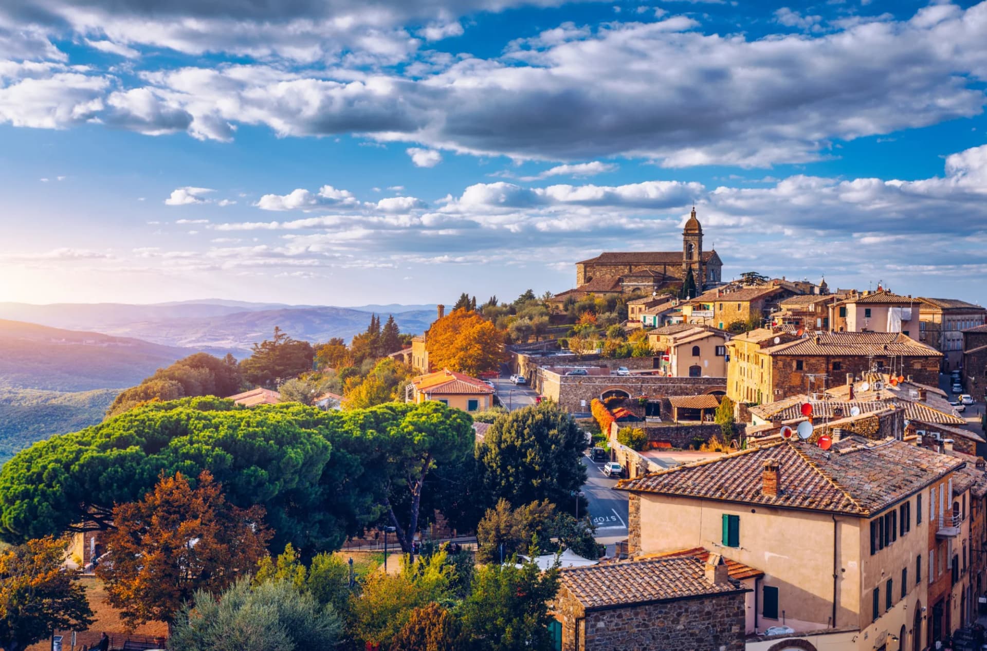 View of Montalcino town, Tuscany, Italy, with terracotta roofs and rolling hills under a cloudy sky.