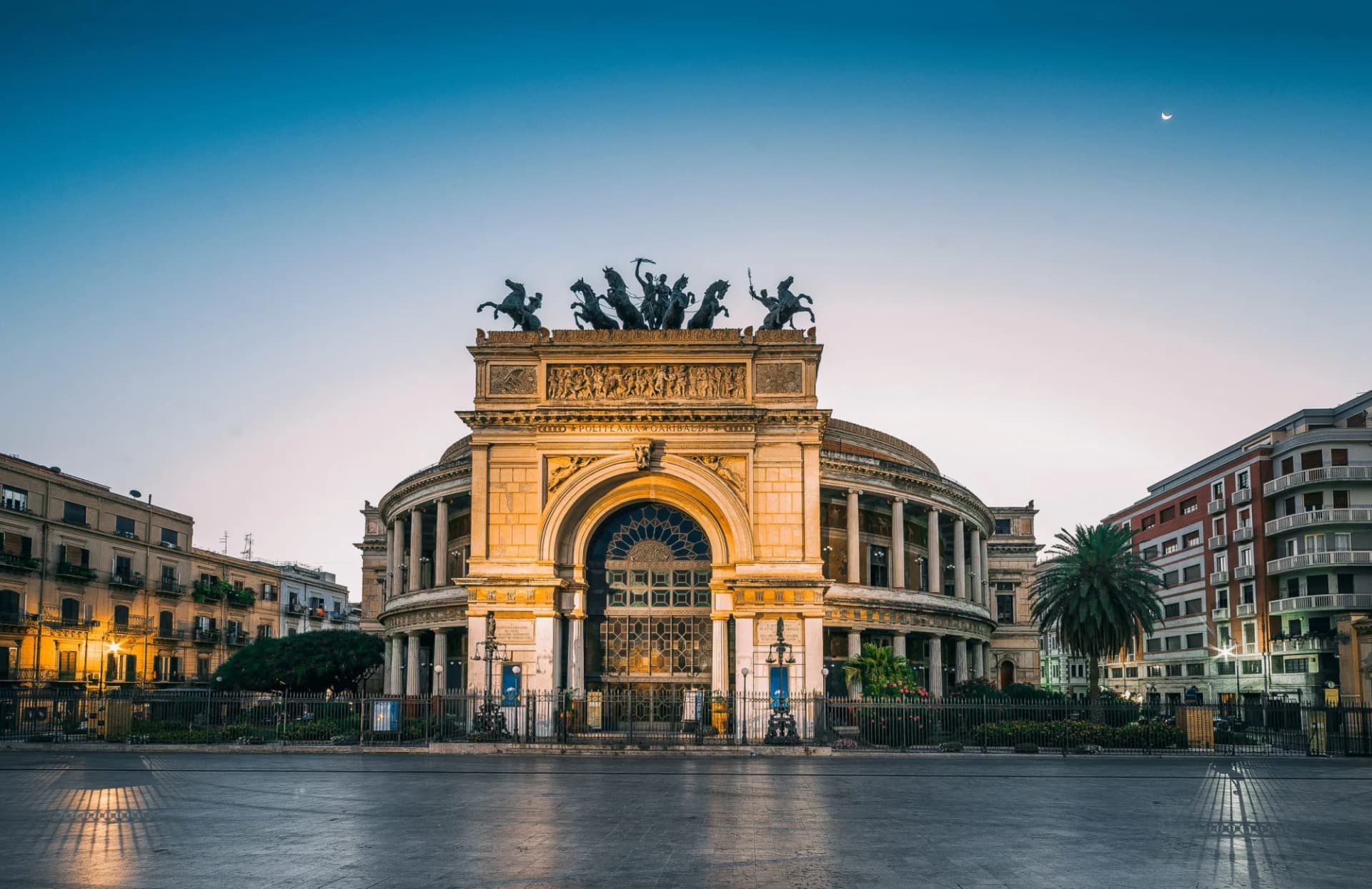 Politeama Garibaldi Theater in Palermo, Sicily, Italy at dusk with a crescent moon.