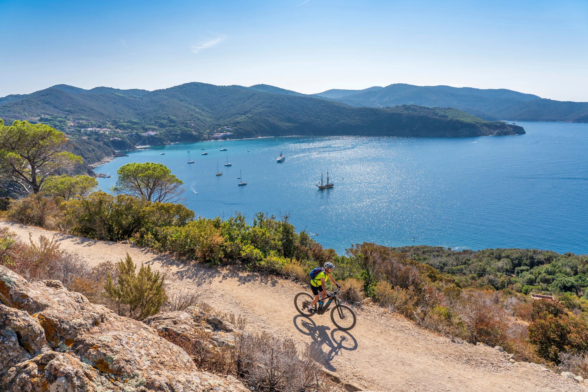 fin kvinde cykler på sin elektriske mountainbike ved kysten af Middelhavet på øen Elba i den toskanske øgruppe Toscana, Italien