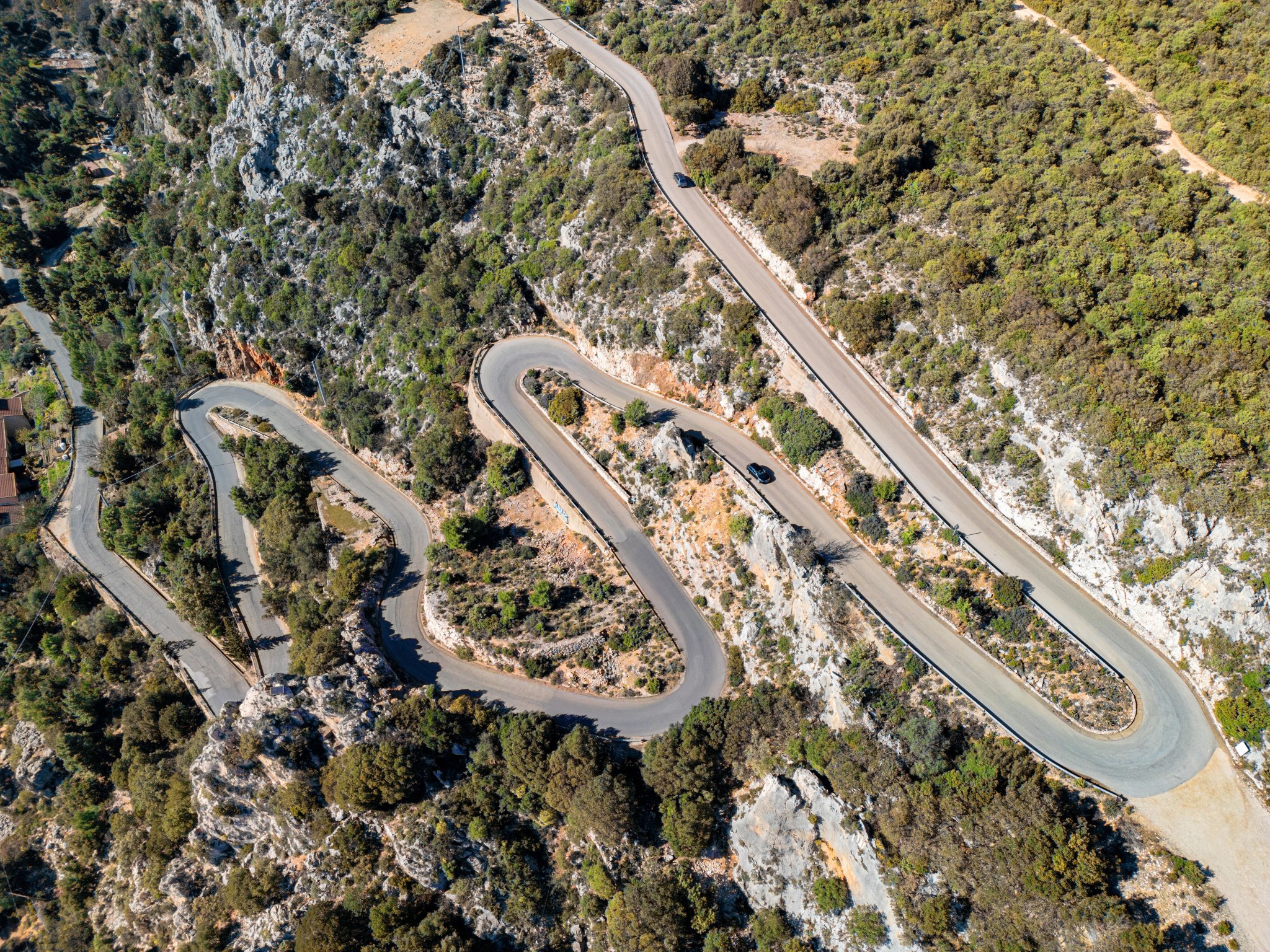 Winding mountain road in Sardinia, Italy – aerial view of scenic serpentine through rugged terrain