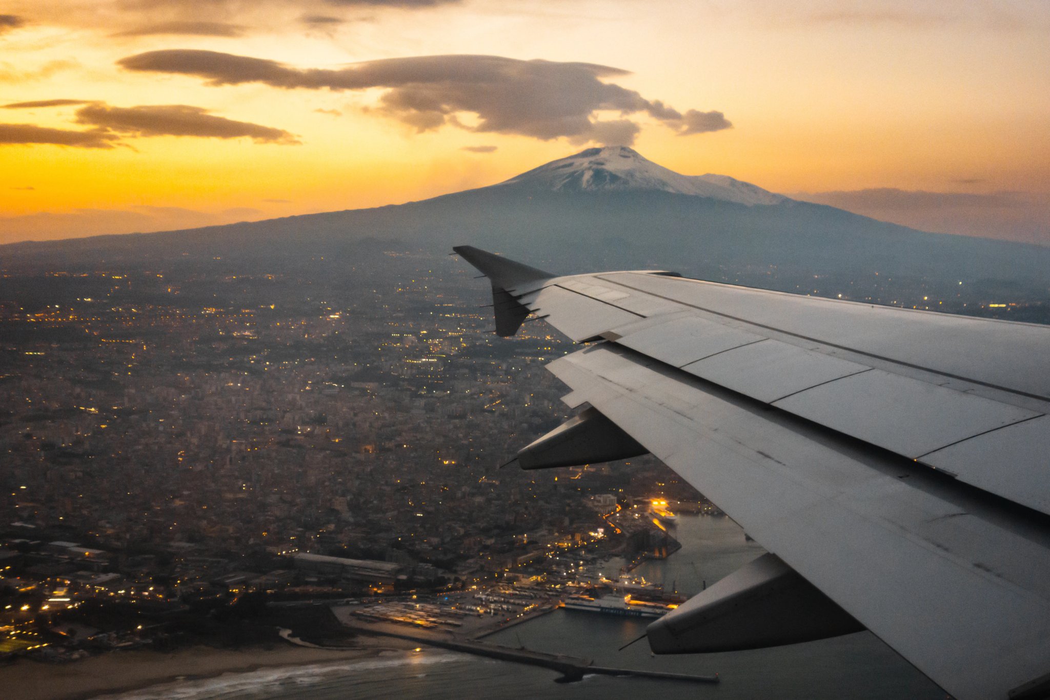 Der Ätna bei Sonnenuntergang. Flugzeugansicht des Ätna mit der Küste der Stadt Catania und ihrem Hafen.