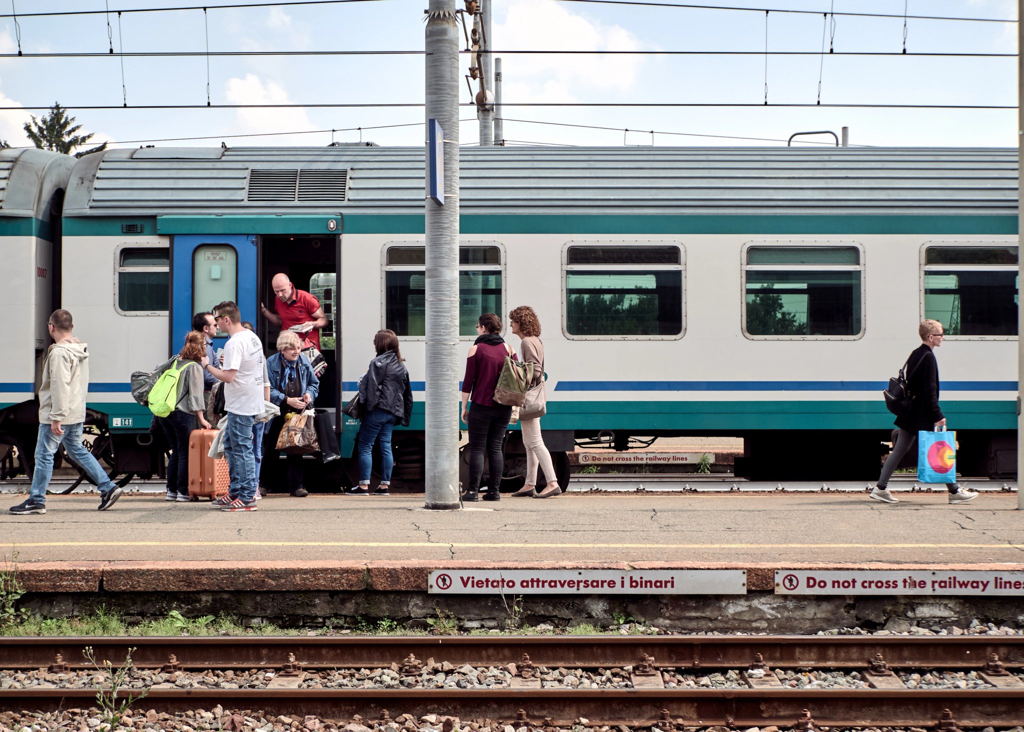 Gruppe von Menschen steigt aus der Lokomotive am Bahnhof Santhià, Italien, am 19. Mai 2018