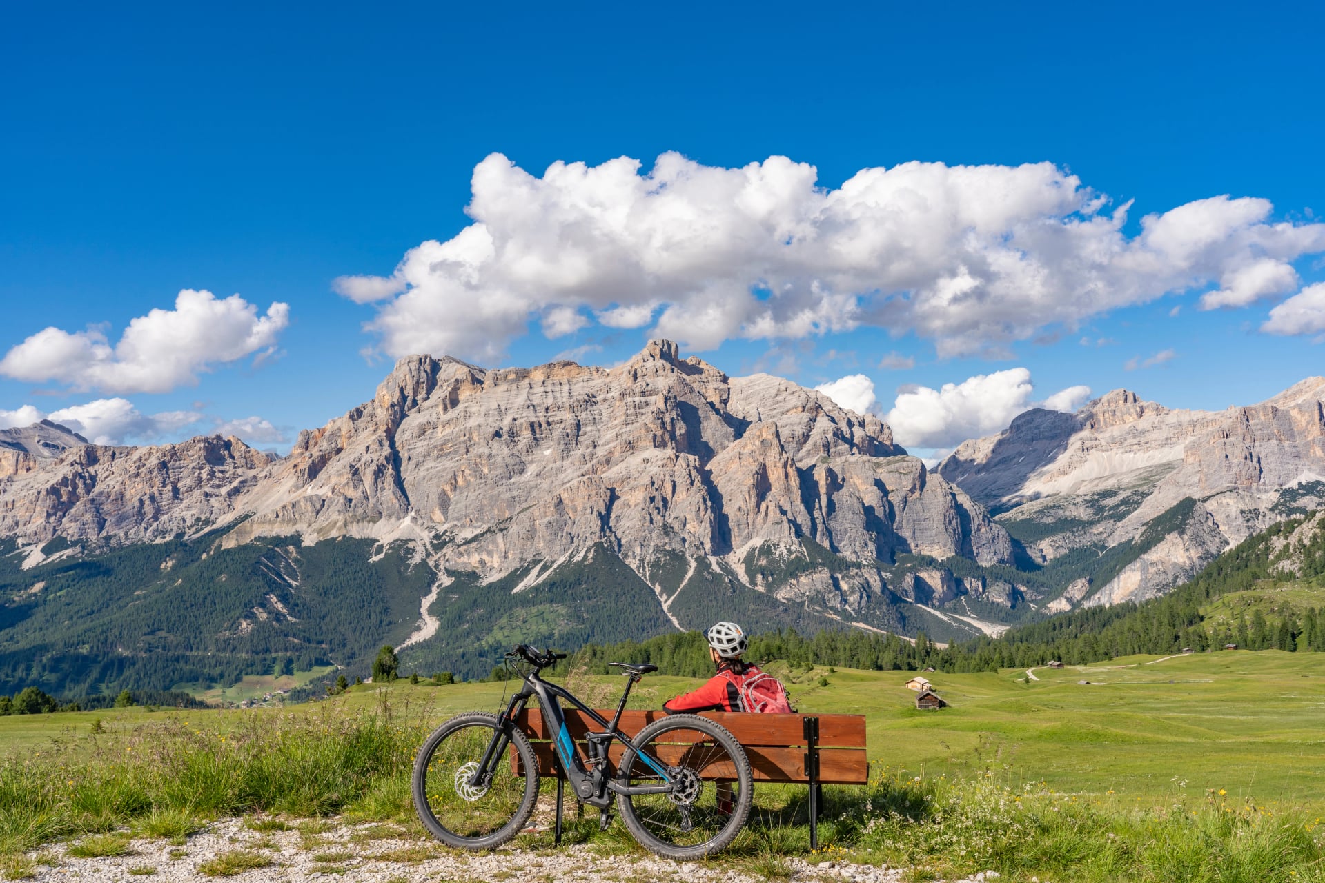 nice and active senior woman riding her electric mountain bike on the Pralongia Plateau in the Alta Badia Dolomites with awesome Sasso die Santa Cruce summit in Backg, South Tirol and Trentino, Italy